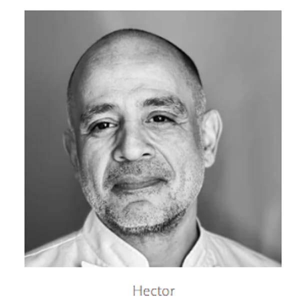Black and white headshot of a smiling man with a beard, identified as Hector.