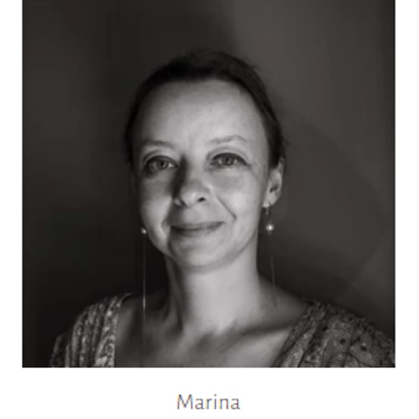Black and white portrait of Marina, a woman with light hair and earrings, smiling.