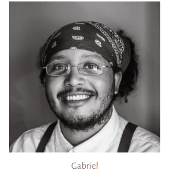 Black and white headshot of a smiling man with glasses, a beard, and a bandana.