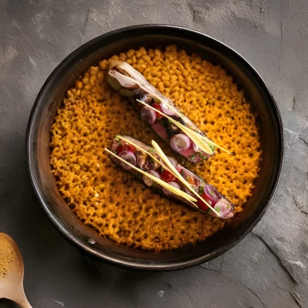 Two skewers of meat and vegetables on a bed of yellow rice in a black bowl.