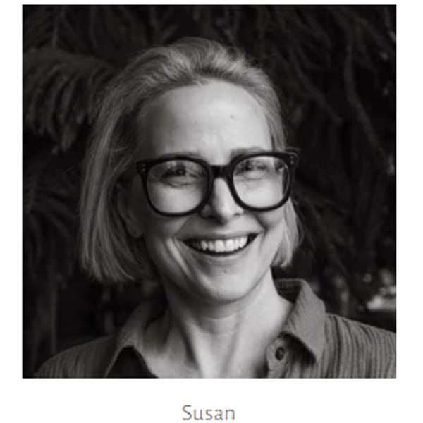 Black and white headshot of a smiling woman with short hair and glasses.