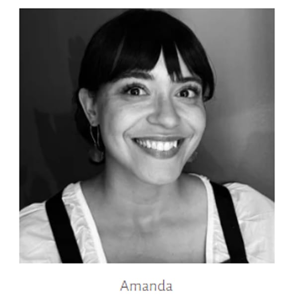 Black and white headshot of a smiling woman with dark hair and bangs.
