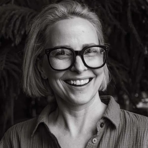Black and white portrait of a smiling woman with short hair and glasses.