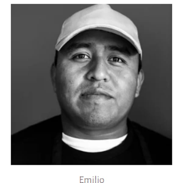 Black and white portrait of Emilio, a man in a white baseball cap and dark shirt.
