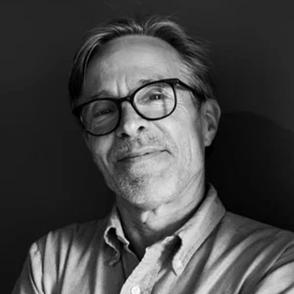 Black and white portrait of a smiling man with glasses and a collared shirt.