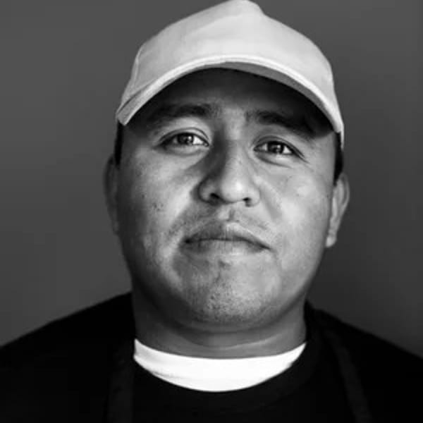 Black and white portrait of a man in a white baseball cap and dark shirt.